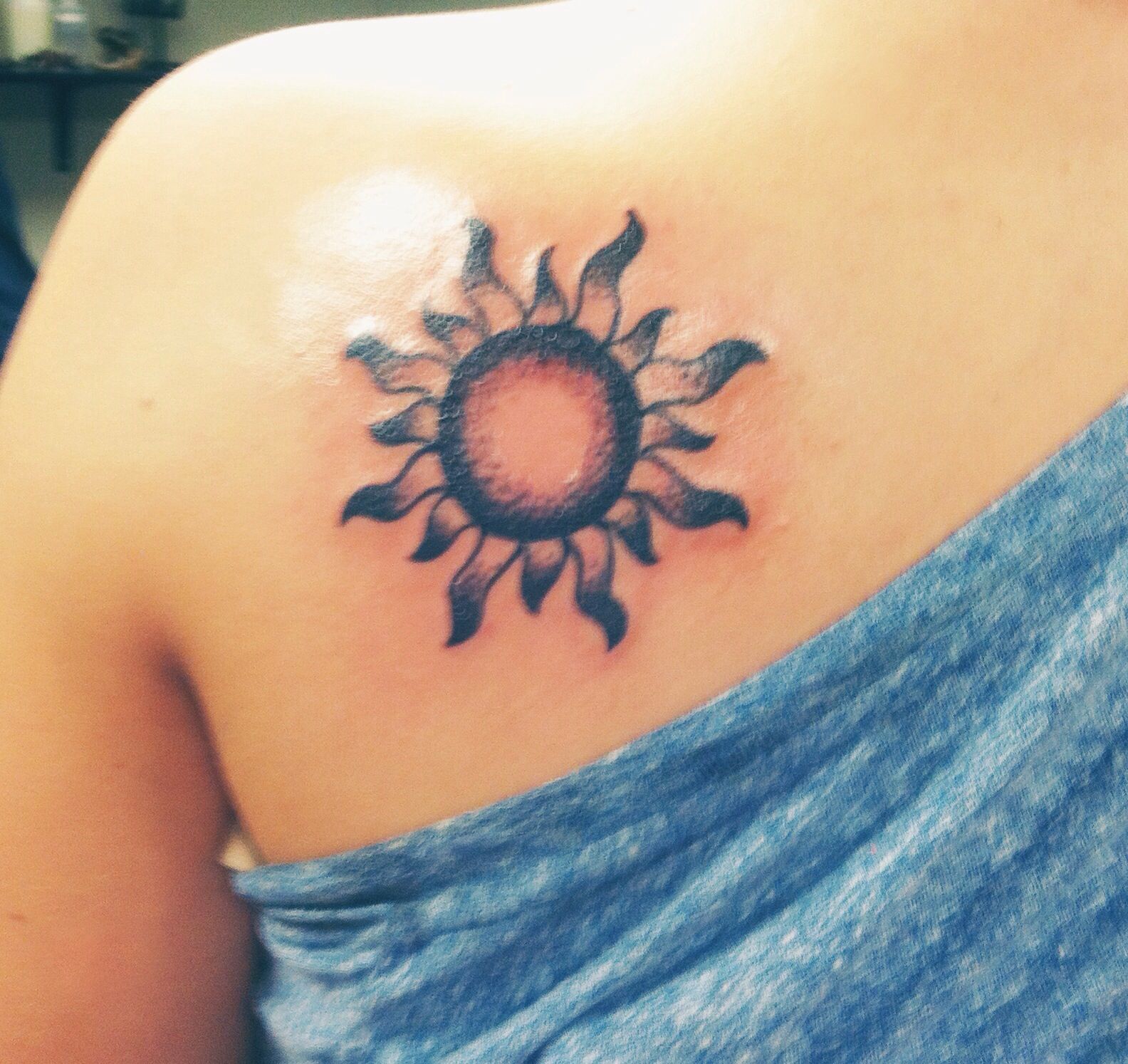 A Woman With A Sun Tattoo On Her Shoulder